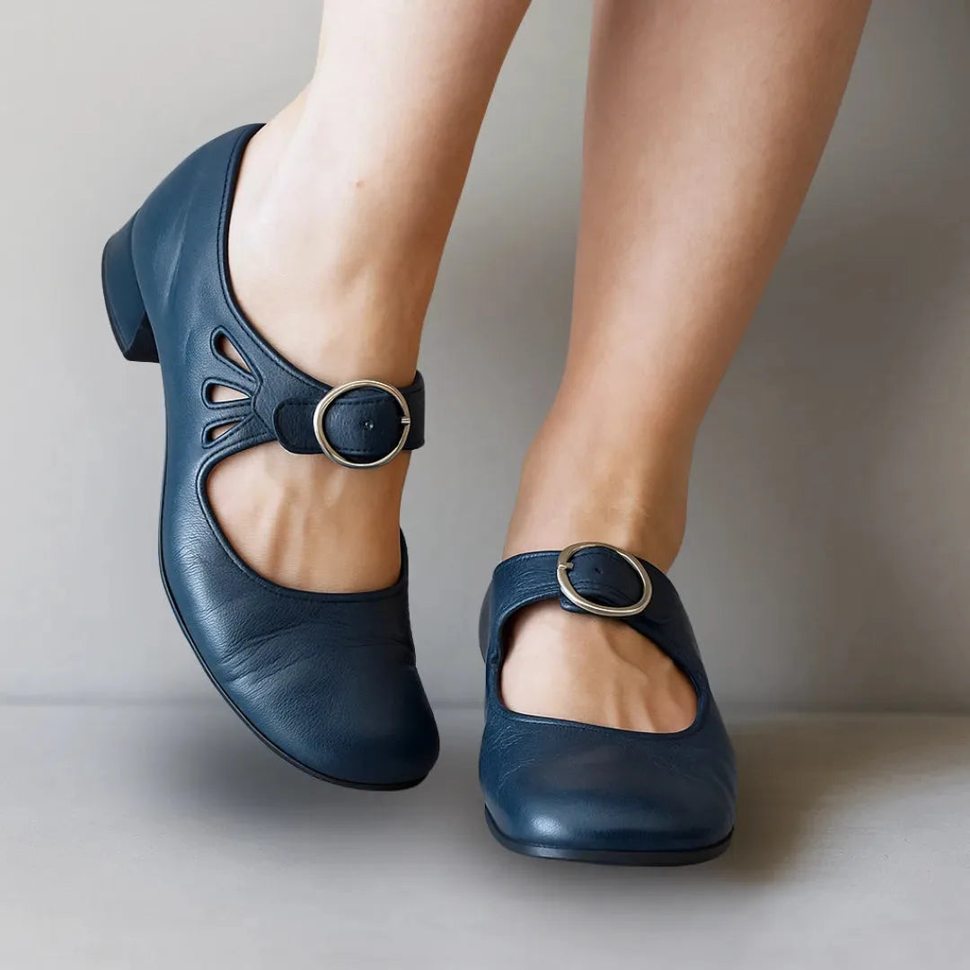 Navy blue leather Mary Jane shoes with silver buckle ankle strap, rounded toe and petal cut-out design, close-up view