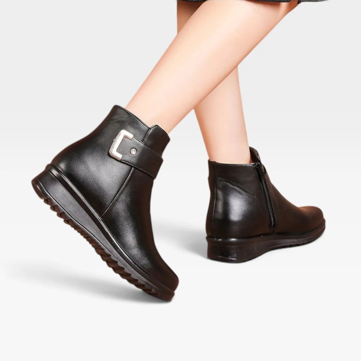 Rear view of model's legs showing the back seam and low wedge heel of black leather ankle boots