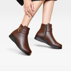 Model standing in brown leather ankle boots, front view showing rounded toe and wedge sole construction