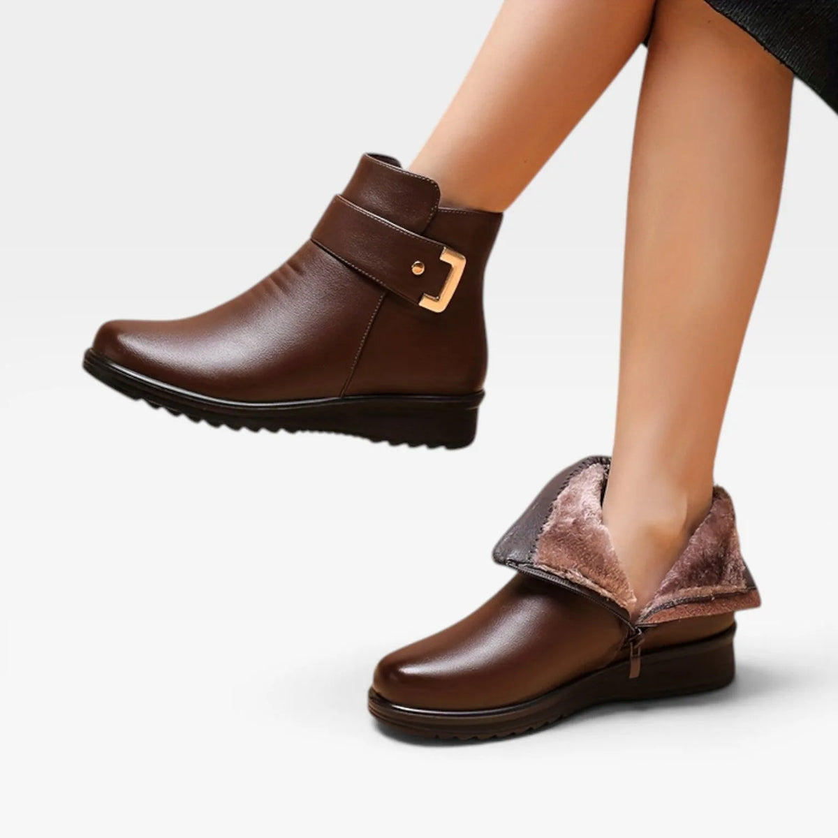 Model walking in brown leather ankle boots, side view showing ankle strap buckle and cushioned sole profile