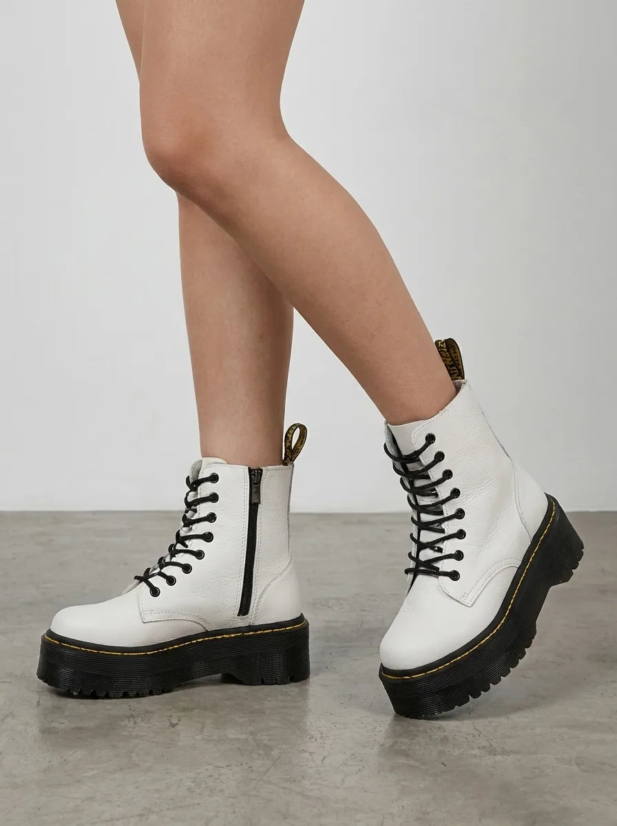 Side view of white leather lace-up platform boots worn with bare legs, showing chunky ridged sole and zip fastening