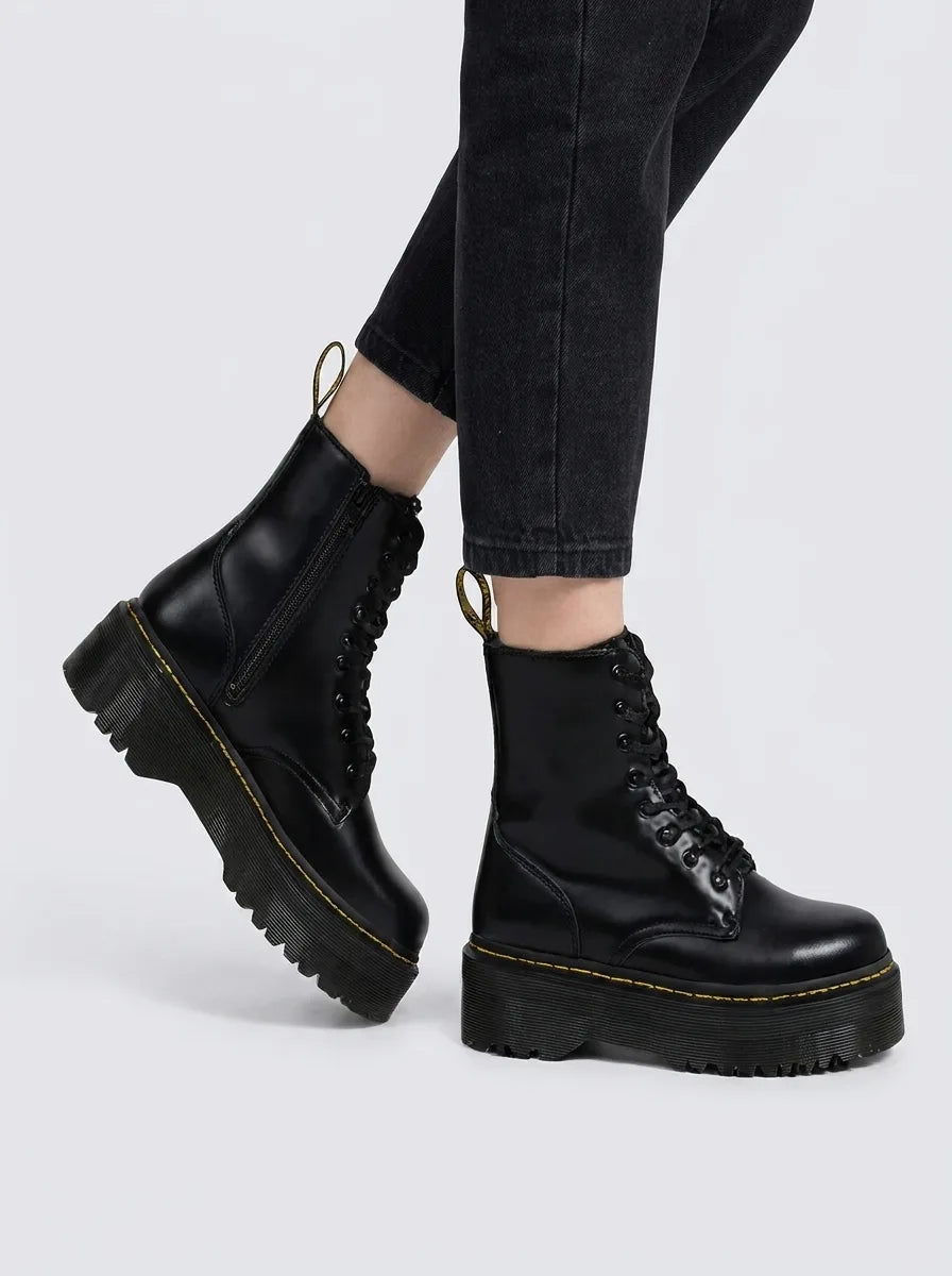 Black leather platform combat boots worn with cropped jeans, side angle highlighting lace-up front and ribbed sole unit