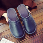 Underside angle of brown leather slippers highlighting the textured non-slip rubber sole