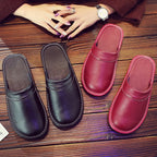 Pair of brown leather slippers photographed from above resting on a polished wood surface