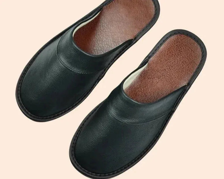 Full pair of brown leather slip-on slippers displayed together against a dark background