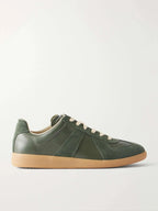 Side view of a forest green leather trainer with suede panels, cream laces and a gum rubber sole