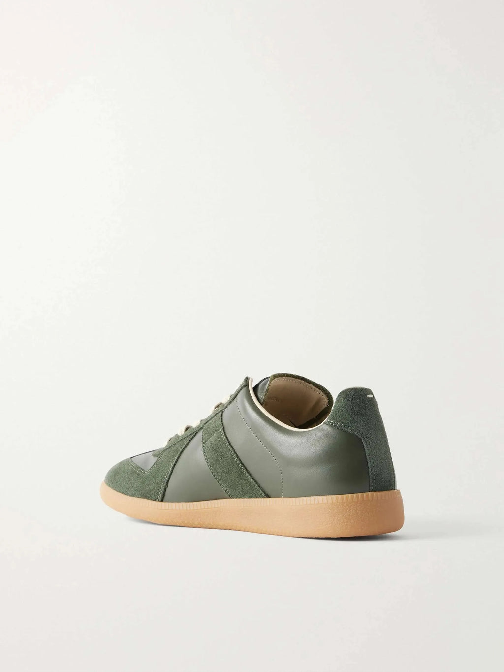 Three-quarter rear view showing the heel tab, suede panel detailing and gum sole of the green leather trainer