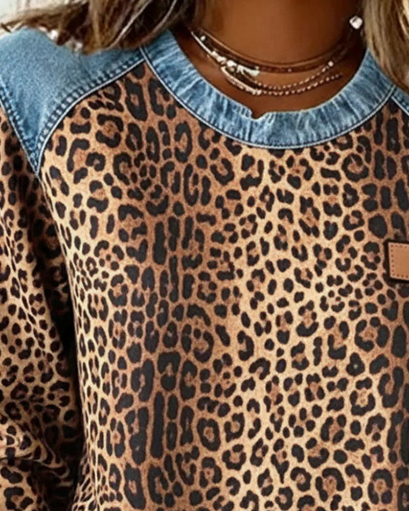 Close-up of denim crew neckline and shoulder seam on brown leopard print sweatshirt with faux leather tab