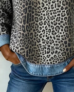 Close-up of denim neckline trim and grey leopard print fabric with small leather tab detail