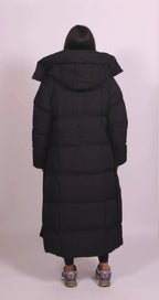 Back view of long black puffer coat highlighting the oversized hood and full-length quilted silhouette