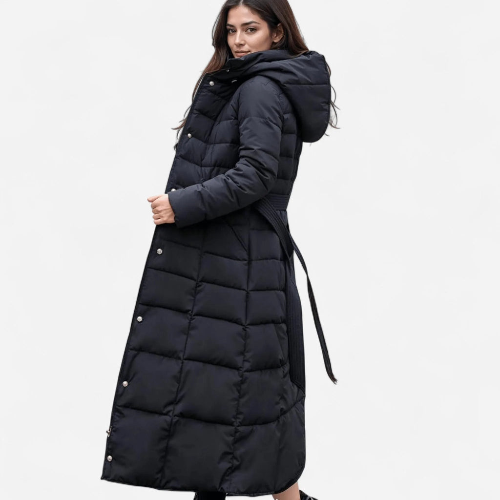 Side view of a black quilted maxi puffer coat with fur-trimmed hood, waist belt and full-length hem