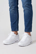 Man wearing white mesh trainers with slim jeans rolled at the ankle, close-up on feet and lower legs