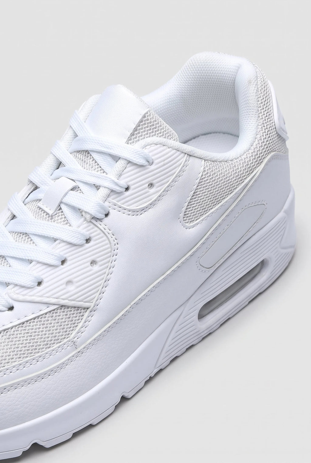 Close-up detail of the white trainer's lacing, mesh panels and textured heel support on toe
