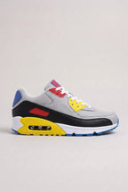 Side view of grey mesh trainer with black, red, yellow and blue colour-block panels and white midsole