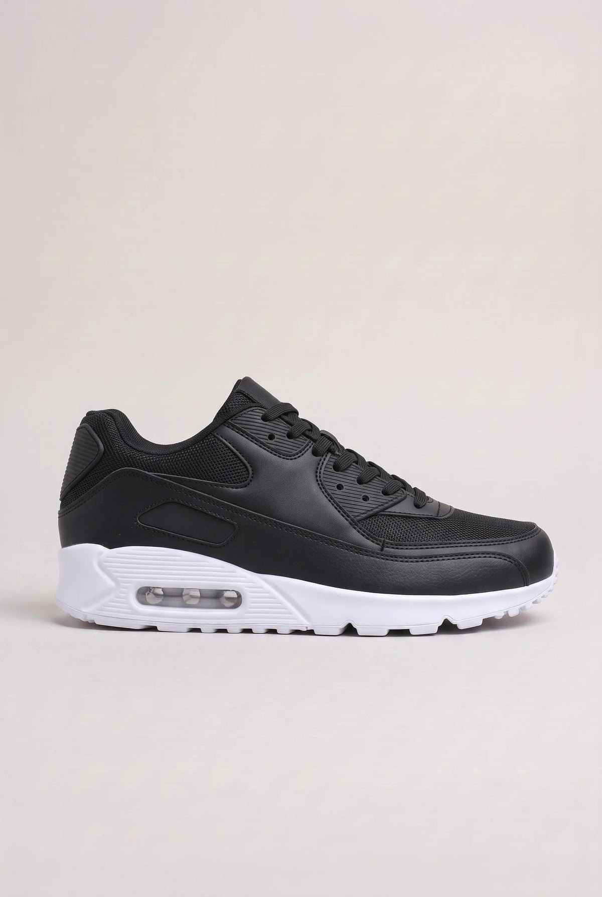 Side profile of black trainer with contrasting white air-cushioned sole and rubber outsole