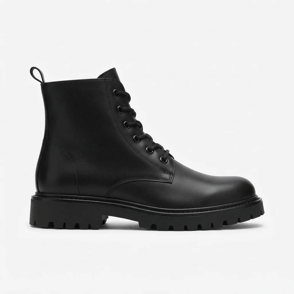 Side profile of a black leather combat boot with lace-up front, round toe and chunky lug sole on a plain background