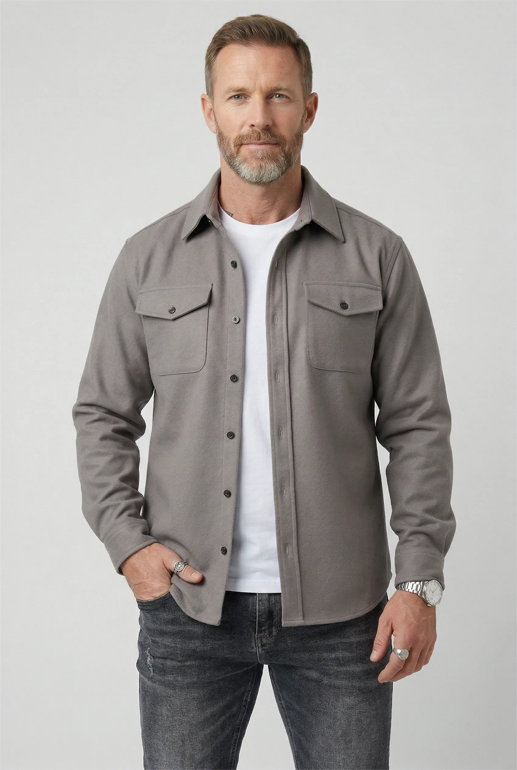 Man wearing a light grey brushed overshirt open over a white T-shirt and dark jeans
