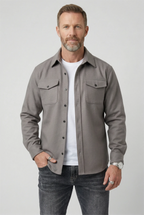 Man wearing a light grey brushed overshirt open over a white T-shirt and dark jeans