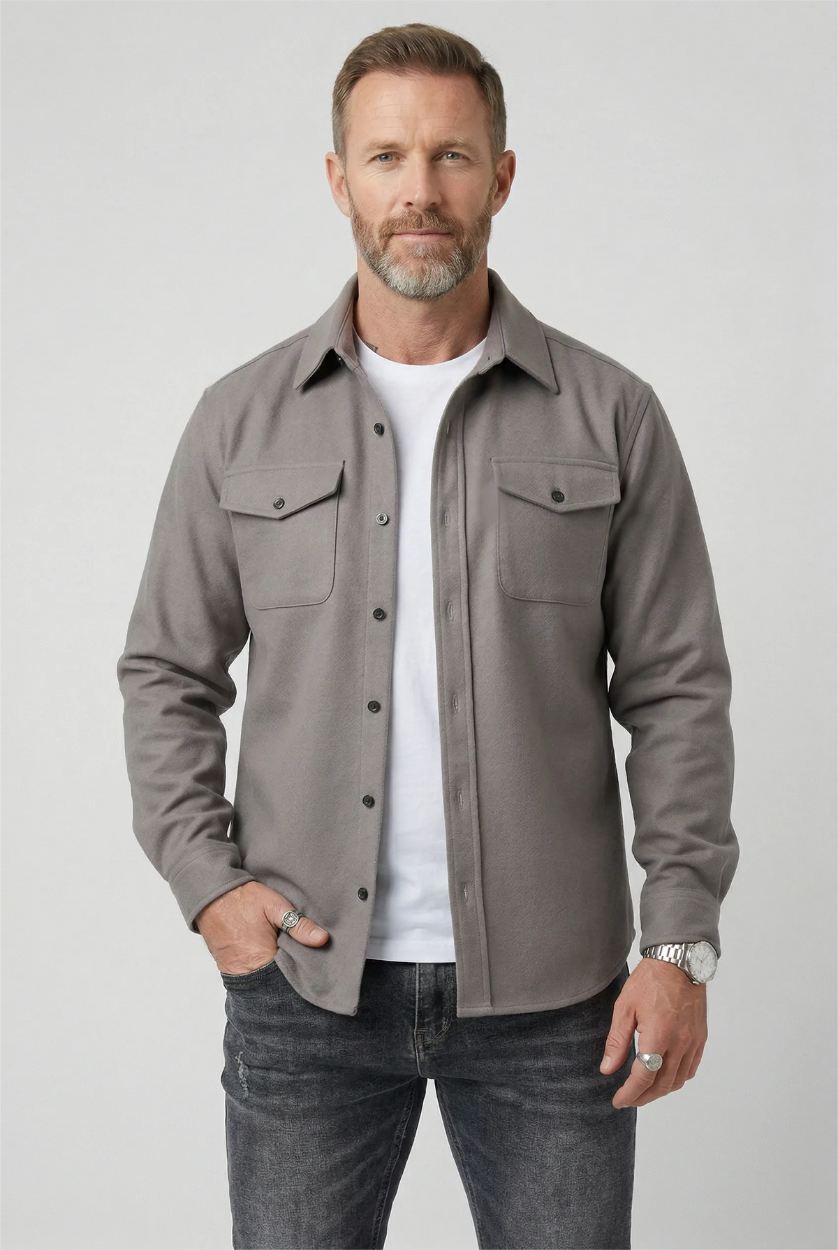 Man wearing a light grey brushed overshirt open over a white T-shirt and dark jeans