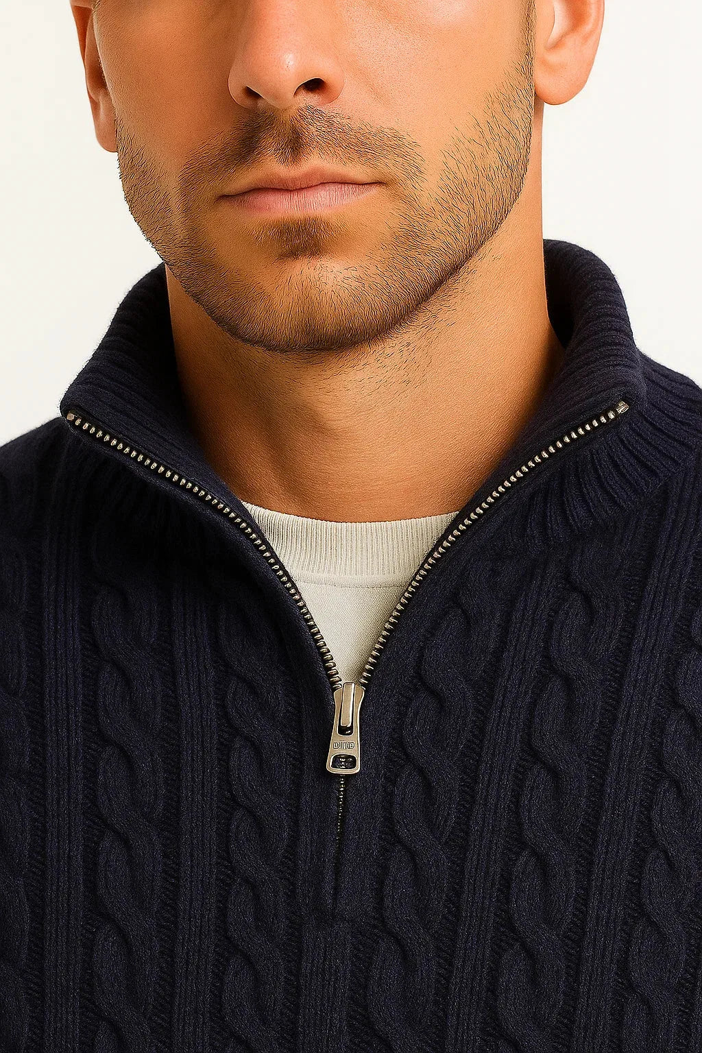 Close-up of the zip pull and ribbed collar detail on a navy cable-knit quarter-zip jumper