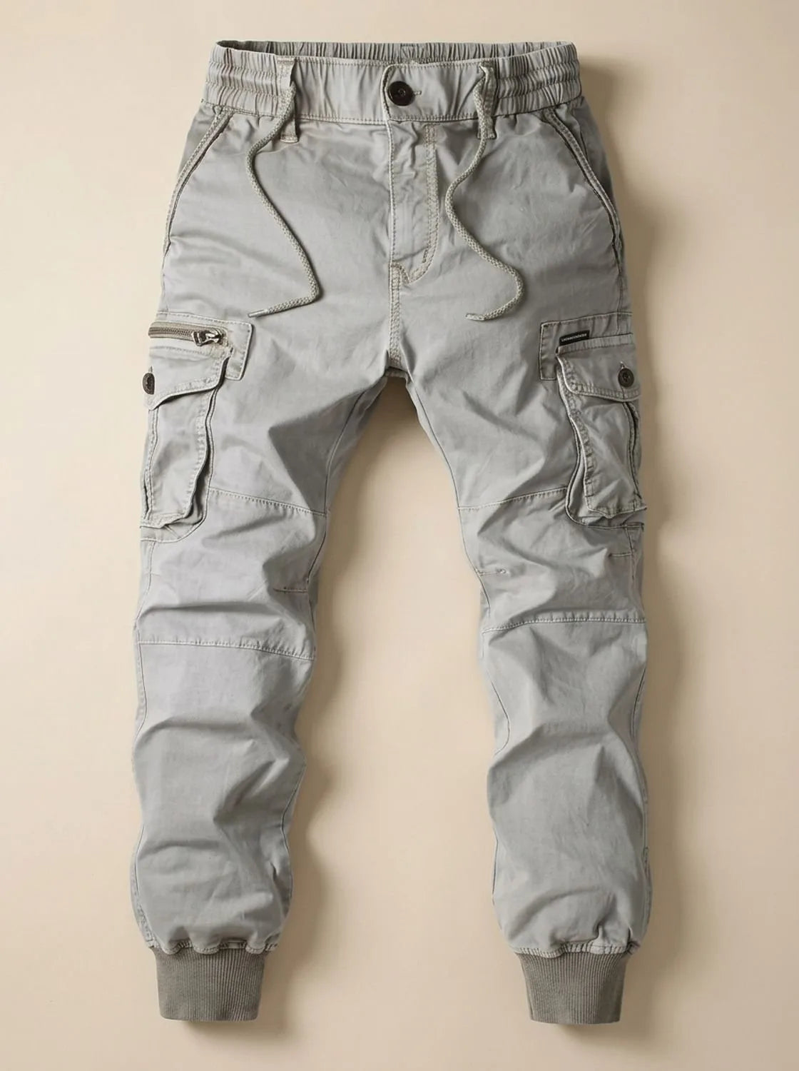 Flat lay of light grey cargo joggers showing side cargo pockets with zip and button fastening