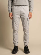 Close-up front view of a man wearing light grey cargo joggers with visible drawstring waistband and cuffed hem