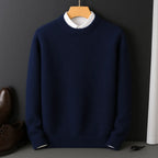 Navy blue knitted jumper on a wooden hanger, layered over a cream collared shirt, front view