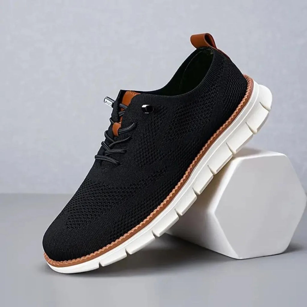 Side profile of black knitted trainer with tan heel pull tab and chunky white ridged outsole