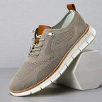 Taupe grey knit trainer with tan leather trim, white laces and white treaded sole shown at an angle
