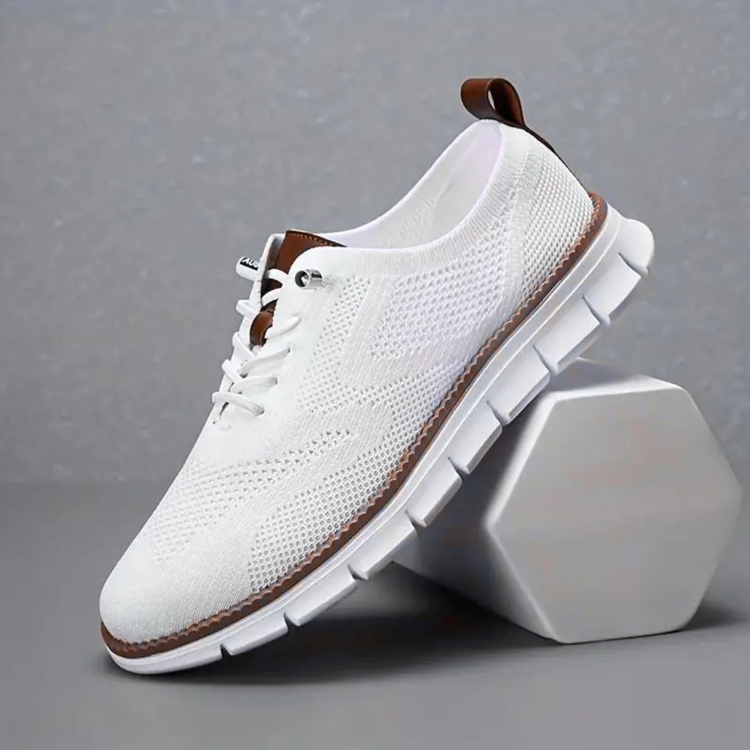 All-white knit trainer with tan leather pull tab, laces and matching white outsole on display