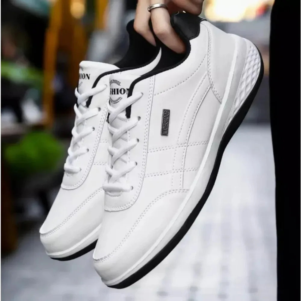 Close-up of white leather trainer with black ankle collar held by hand, showing lace-up front and stitched toe panel
