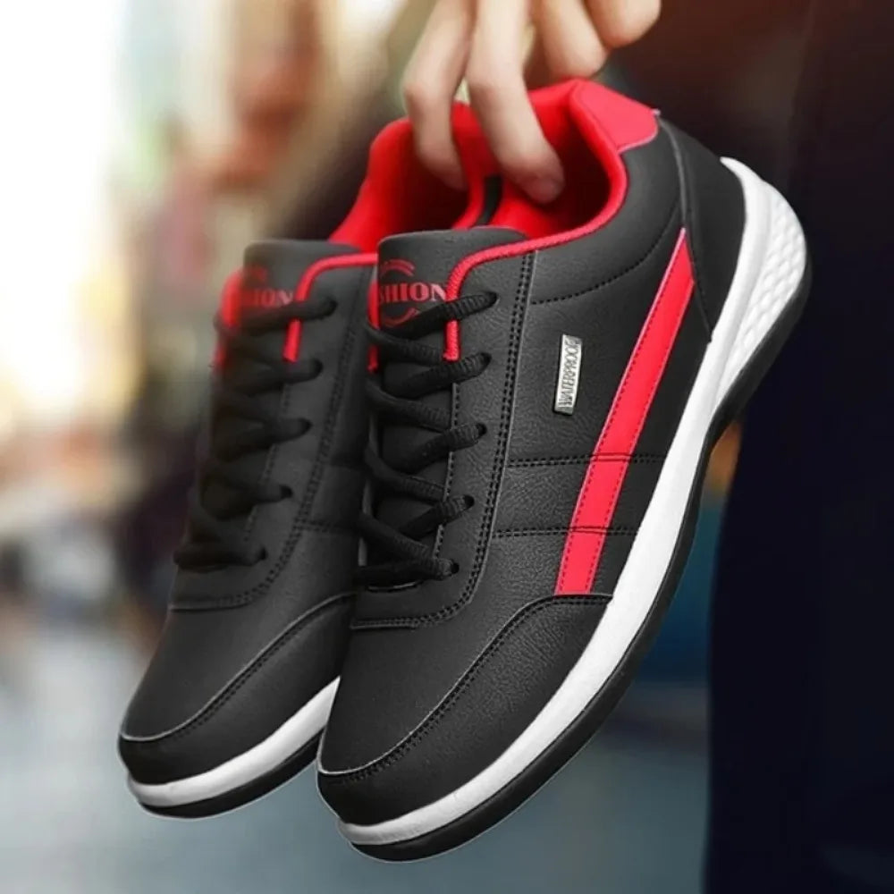 Pair of black trainers with red stripes and red lining held together by hand, showing white midsole