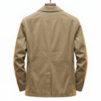 Back view of khaki cotton blazer on a wooden hanger, showing centre seam, shoulder structure and side vents