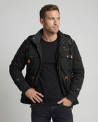 Front view of a man wearing a black multi-pocket cotton field jacket open over a black t-shirt and dark jeans