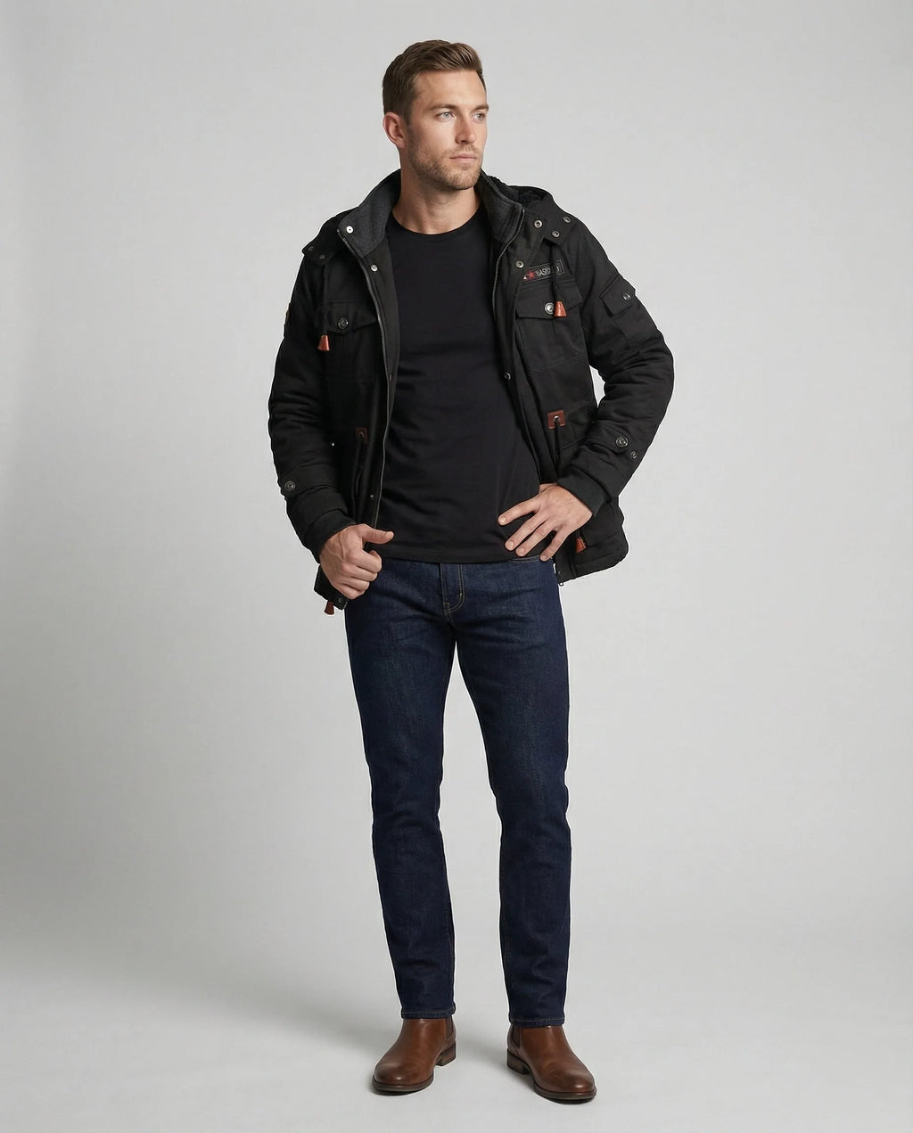 Full-length side view showing the black field jacket paired with dark denim and brown leather Chelsea boots