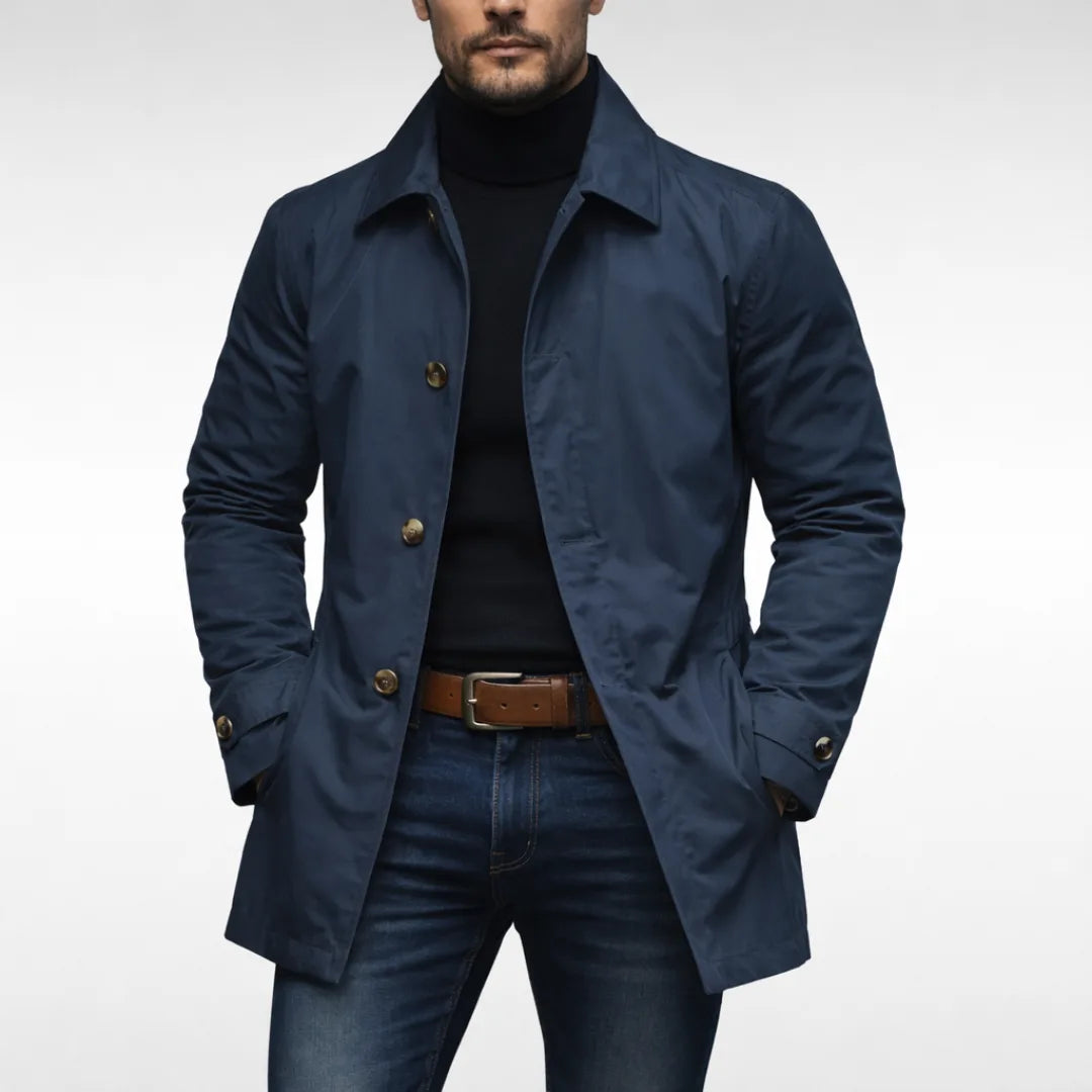 Man wearing a navy blue trench coat buttoned over a black polo neck, paired with a brown leather belt