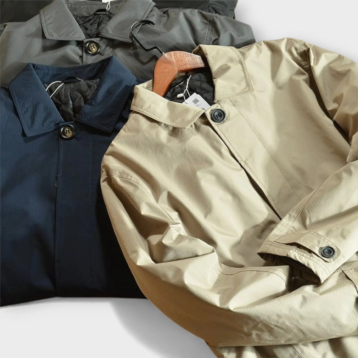 Close-up of the collar and top button on a beige trench coat, highlighting the stitching and fabric texture