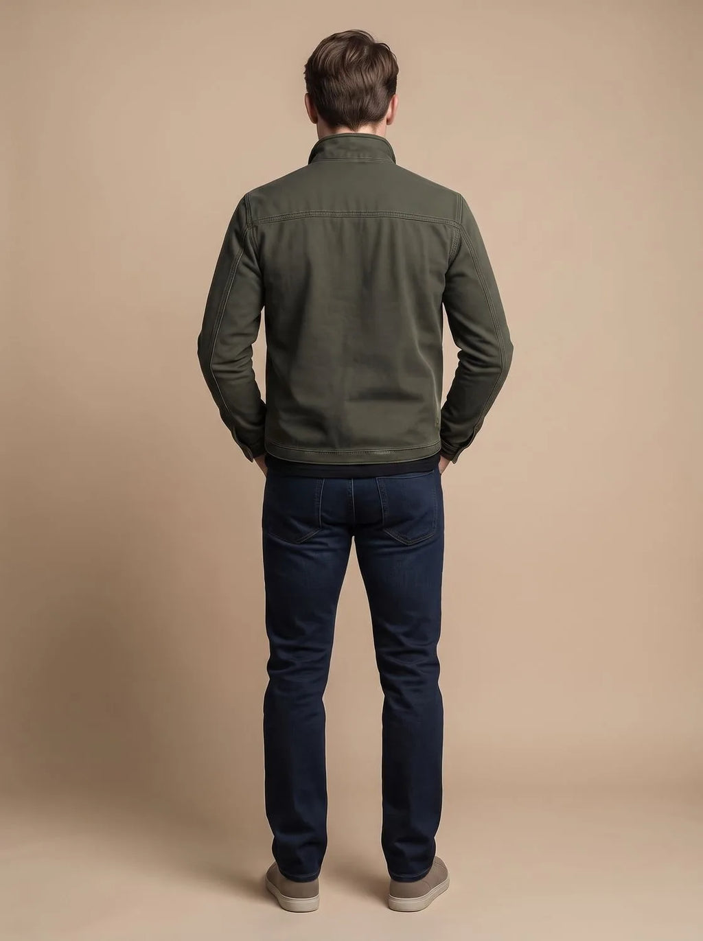Rear view of a man wearing the olive green jacket with dark jeans, showing the back panel seams