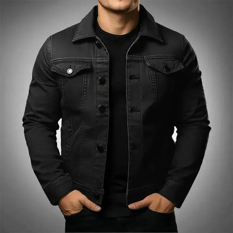 Man wearing a black denim trucker jacket fully buttoned over a black t-shirt, front view close up