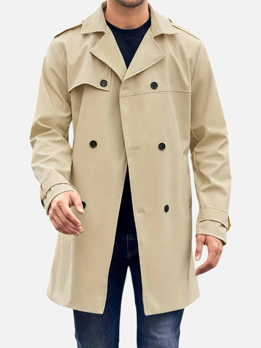 Man wearing a beige double-breasted trench coat open over a navy jumper, front view showing notched lapel and buttons
