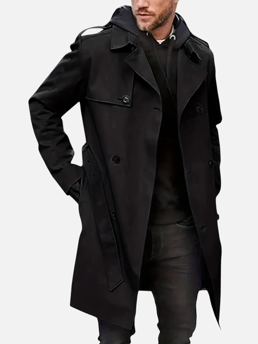 Black double-breasted trench coat worn over a dark hoodie, front view showing tie belt at the waist