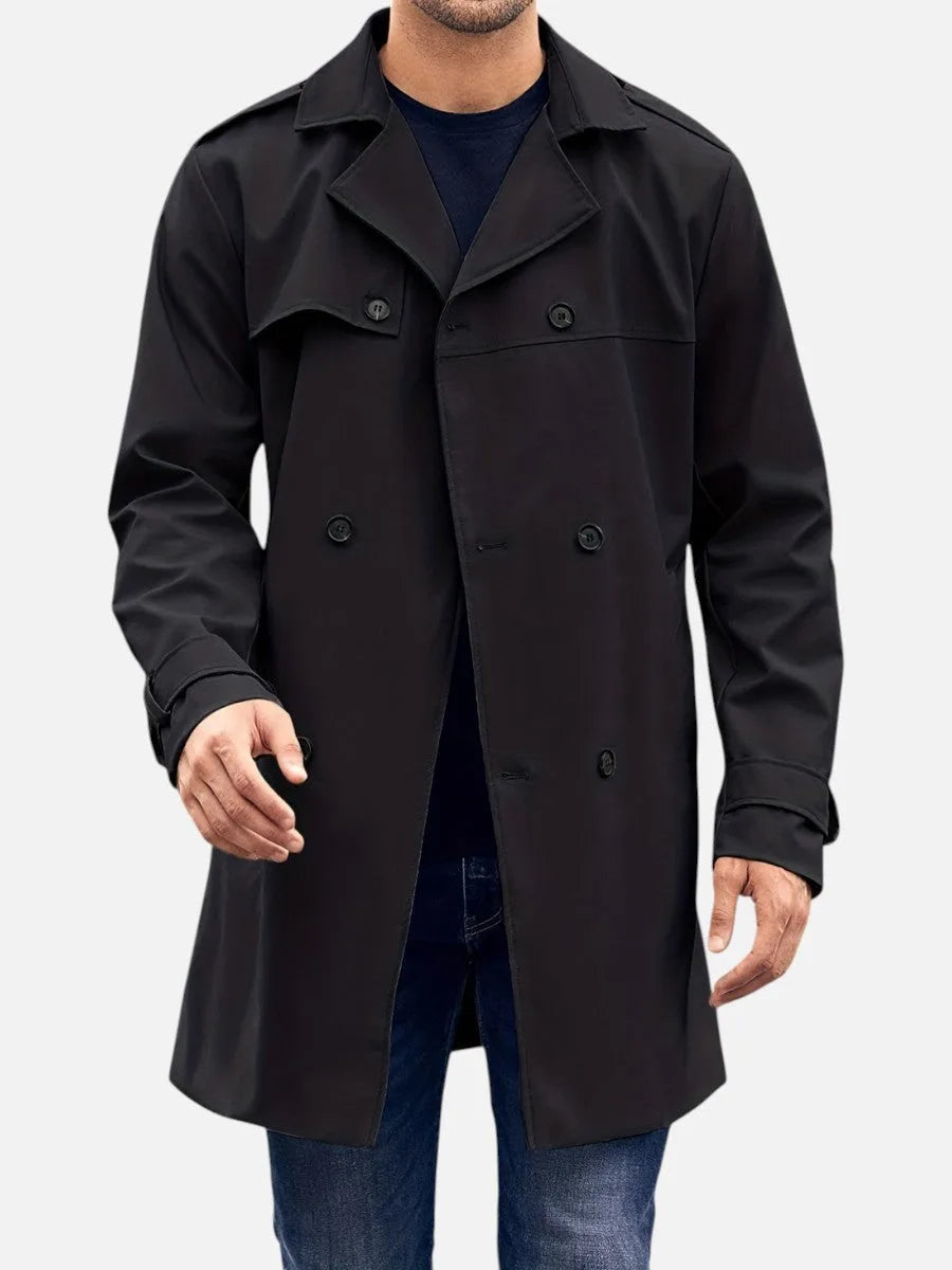 Black trench coat worn open over a navy jumper, front view showing button placket and structured lapel