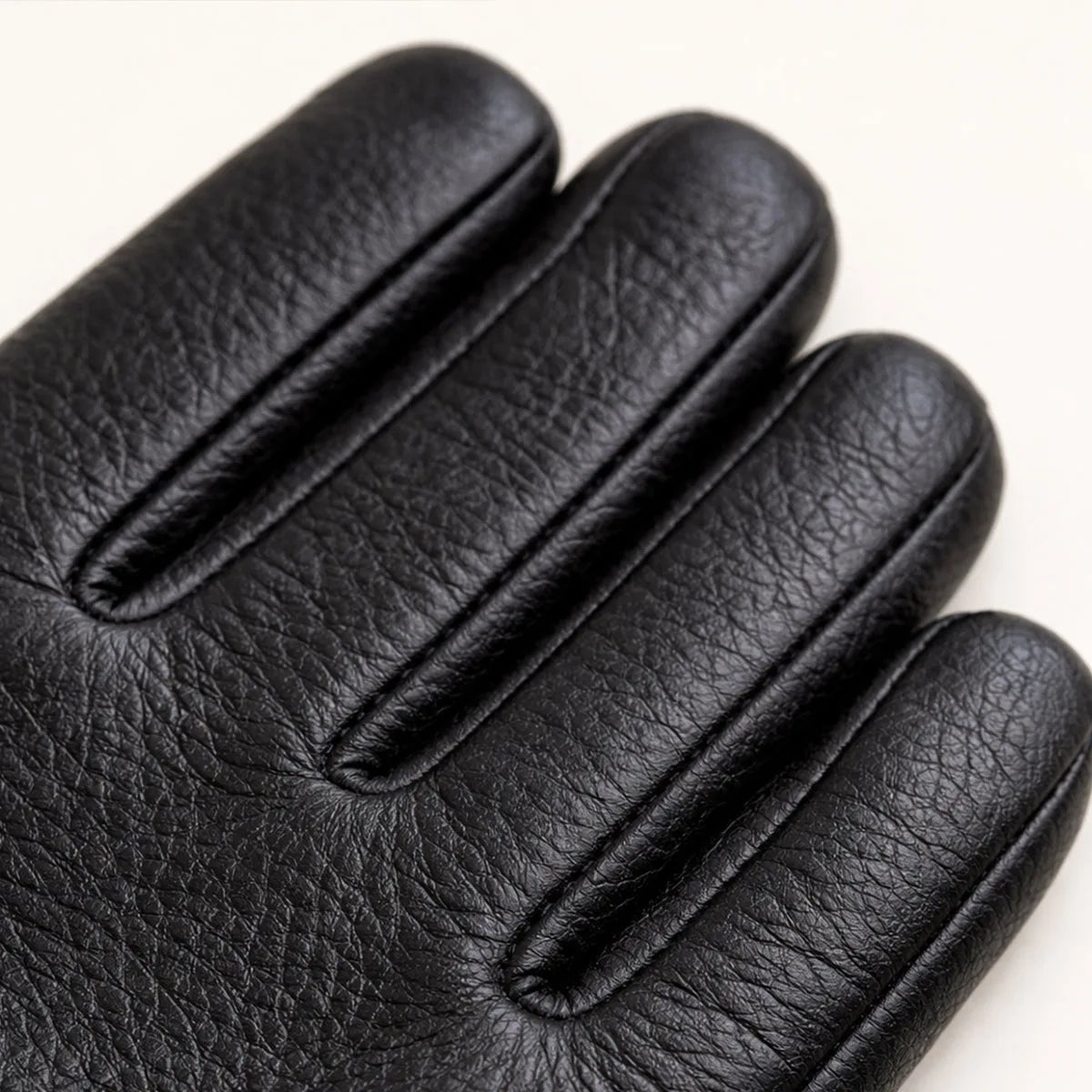 Macro detail of black leather glove fingers showing natural grain texture and ribbed seam construction