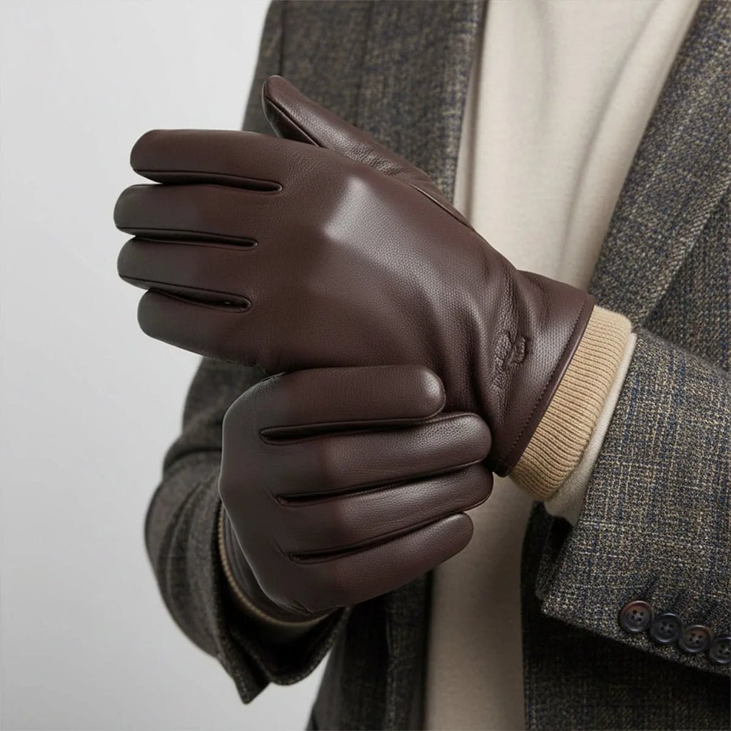 Man in a tweed blazer wearing brown leather gloves, hands clasped together over a cream jumper