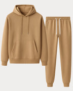 Flat lay of a khaki hooded sweatshirt and matching jogger tracksuit on a plain background