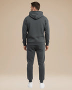 Man wearing the navy tracksuit from a three-quarter angle showing the hood and pocket detail