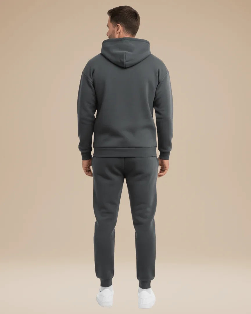 Man wearing the navy tracksuit from a three-quarter angle showing the hood and pocket detail