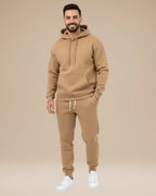 Man wearing a khaki hoodie and jogger tracksuit with white trainers, front view