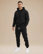 Man modelling a black hoodie and jogger set with white trainers, front view