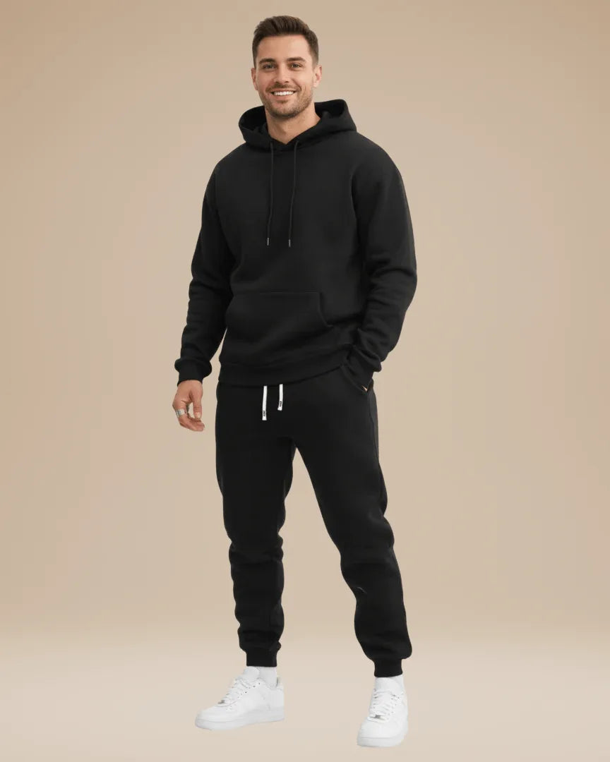 Man modelling a black hoodie and jogger set with white trainers, front view
